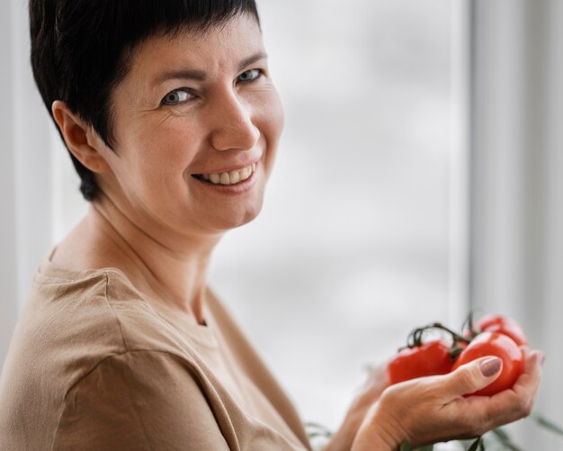 Zijaanzicht van smileyvrouw met inlandse tomaten