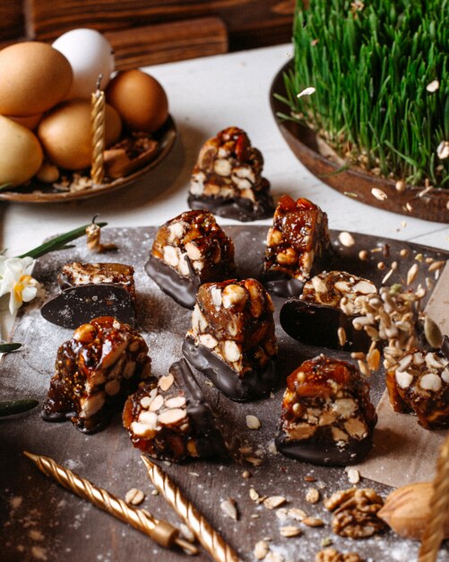 Zijaanzicht van snoep met karamel pure chocolade en geroosterde hazelnoten op een houten bord