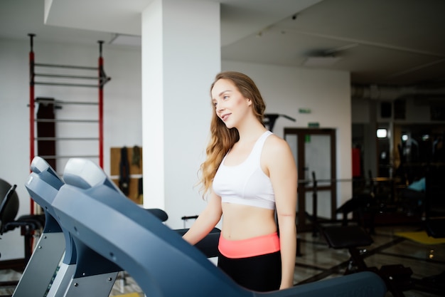 Zijaanzicht van sportieve vrouw uitoefenen op loopband in de sportschool