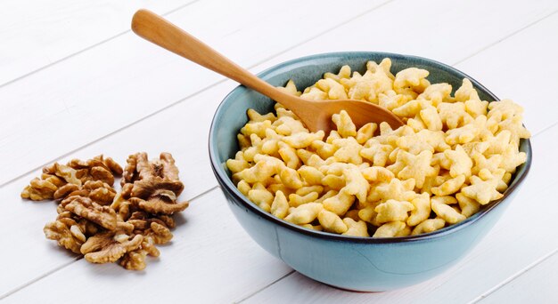 Zijaanzicht van stervormige cornflakes in een kom en walnoten op de tafel