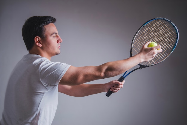 Gratis foto zijaanzicht van tennisspeler poseren met racket en bal