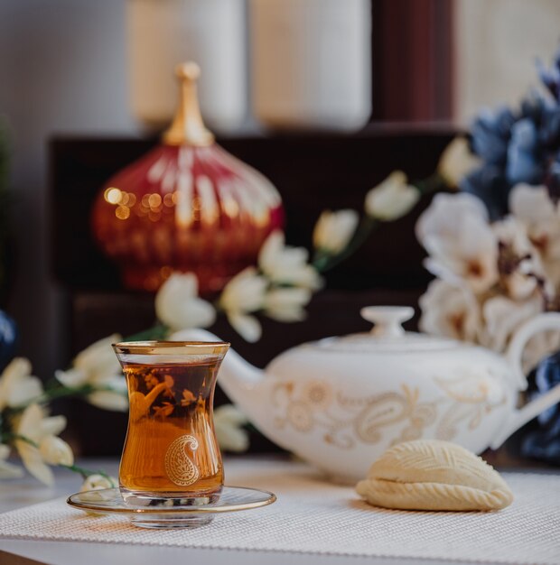 Zijaanzicht van Turkse azeri traditionele peervormige glas voor zwarte thee armudu met shekerbura op tafel