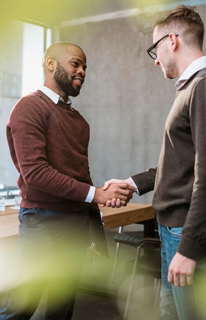 Gratis foto zijaanzicht van twee mannen handshaking in overleg na een vergadering