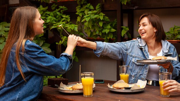 Zijaanzicht van twee vrouwen die elkaar hamburgers voeden