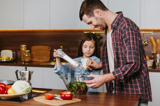 Zijaanzicht van vader met dochter die voedsel in de keuken voorbereidt