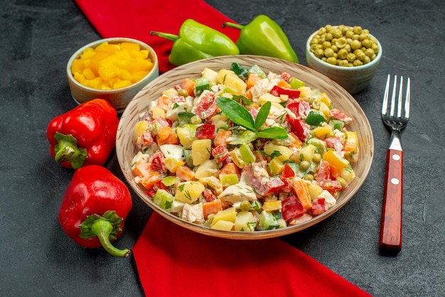 Zijaanzicht van vegetarische salade op rood servet en met groenten en vork aan de zijkant op donkergrijze achtergrond