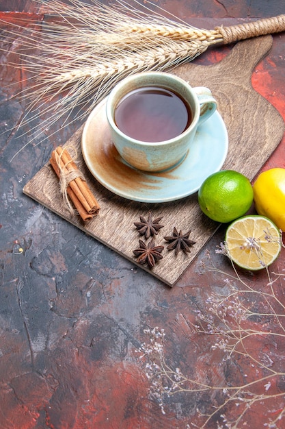 Zijaanzicht van ver een kopje thee een kopje thee kaneelstokjes steranijs citrusvruchten op het bord