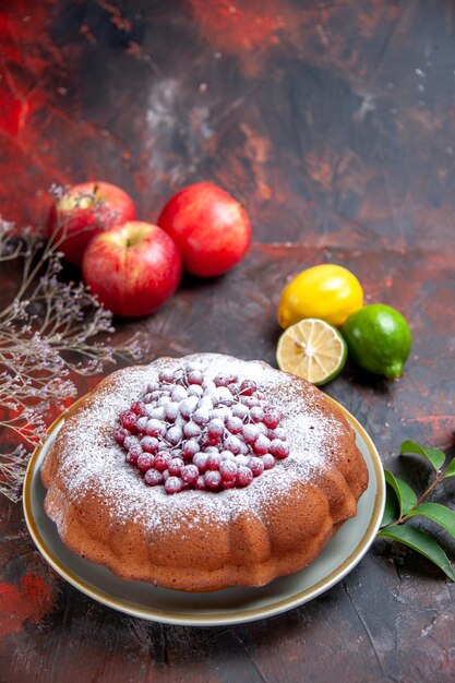 Zijaanzicht van verre cake een cake met aangedreven suiker drie appels citrusvruchten takken bladeren