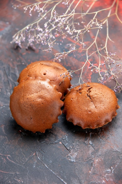 Gratis foto zijaanzicht van verre smakelijke cupcakes smakelijke cupcakes op de blauwrode achtergrond naast de takken