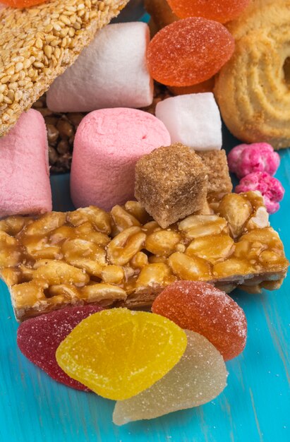 Zijaanzicht van verschillende snoep honing bars van noten marshmallow marmelade snoepjes en koekjes op blauw