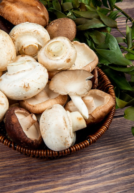 Zijaanzicht van verse champignons in een rieten mand op rustiek hout