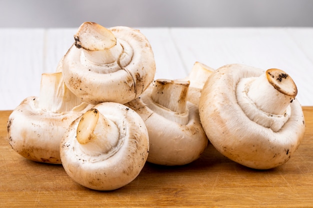 Zijaanzicht van verse champignonschampignon op houten raad op witte achtergrond