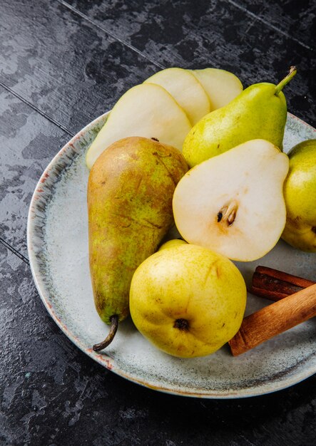 Zijaanzicht van verse rijpe peren en plakjes peren op een plaat