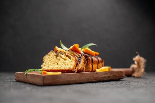 Zijaanzicht van versgebakken zachte cakeplakken op houten snijplank op donkere tafel