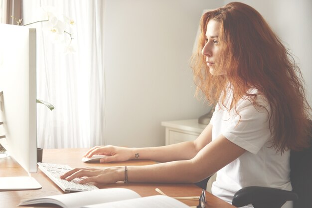 Zijaanzicht van vertrouwen vrouwelijke ontwerper met losse haren kijken naar het computerscherm