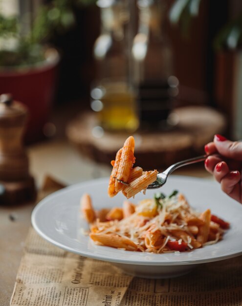 Zijaanzicht van vork met pasta met tomatensaus en Parmezaanse kaas