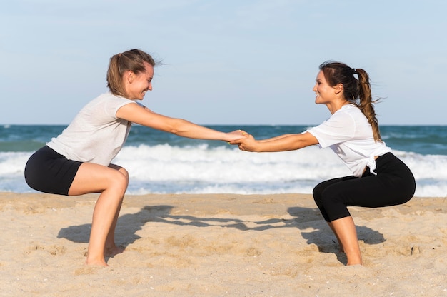 Zijaanzicht van vrienden die samen op het strand uitoefenen