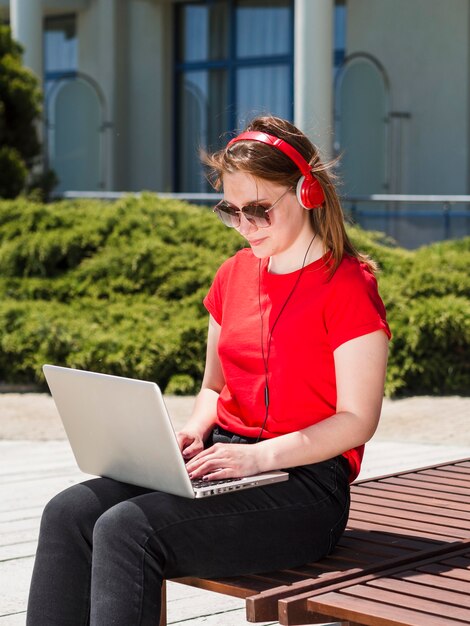 Zijaanzicht van vrouw die buiten aan laptop werkt