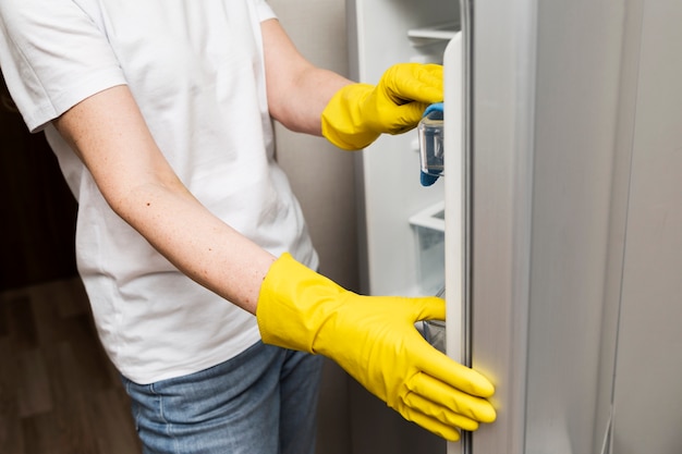 Gratis foto zijaanzicht van vrouw die de koelkast schoonmaakt