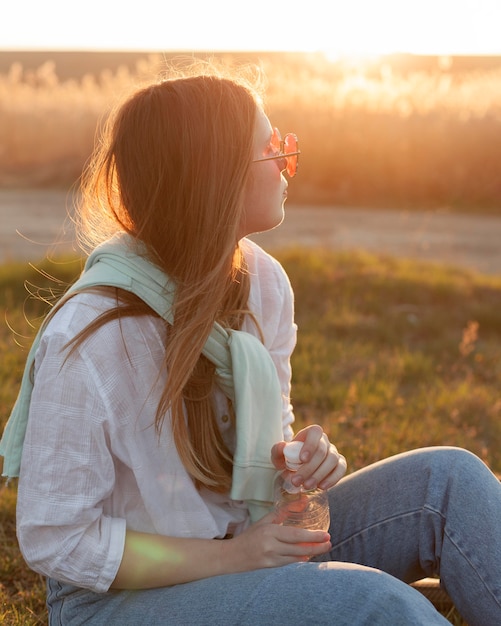 Zijaanzicht van vrouw die met zonnebril in de zonsondergang ontspannen