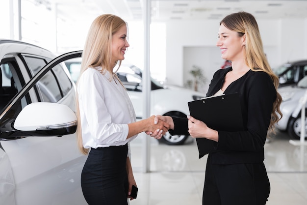 Gratis foto zijaanzicht van vrouw die nieuwe auto koopt