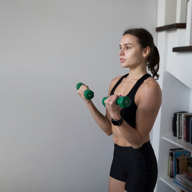 Gratis foto zijaanzicht van vrouw die thuis sporten doet