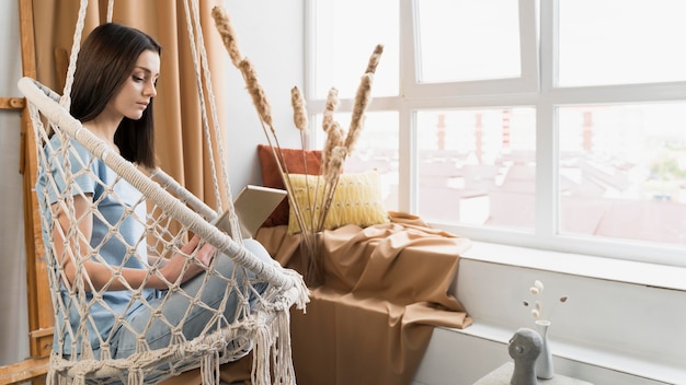 Zijaanzicht van vrouw die van huis aan tablet werkt