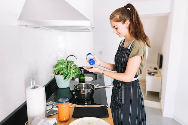 Zijaanzicht van vrouw die voedsel in de keuken voorbereidt