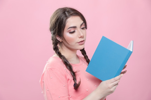 Gratis foto zijaanzicht van vrouw die zich voordeed tijdens het lezen van een boek