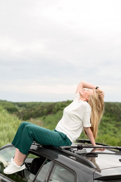 Zijaanzicht van vrouw het stellen bovenop auto