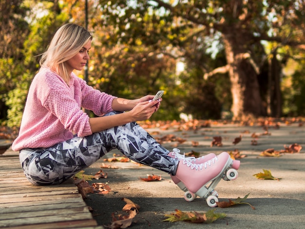 Zijaanzicht van vrouw in beenkappen die telefoon bekijken