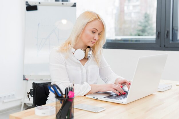 Zijaanzicht van vrouw in rolstoel die aan laptop werkt