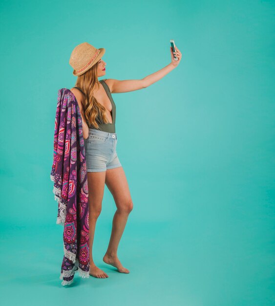 Zijaanzicht van vrouw in strandkleding die een selfie neemt