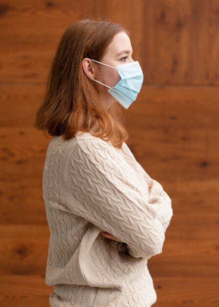 Zijaanzicht van vrouw met gekruiste armen die een medisch masker dragen