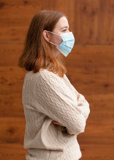 Zijaanzicht van vrouw met gekruiste armen die een medisch masker dragen