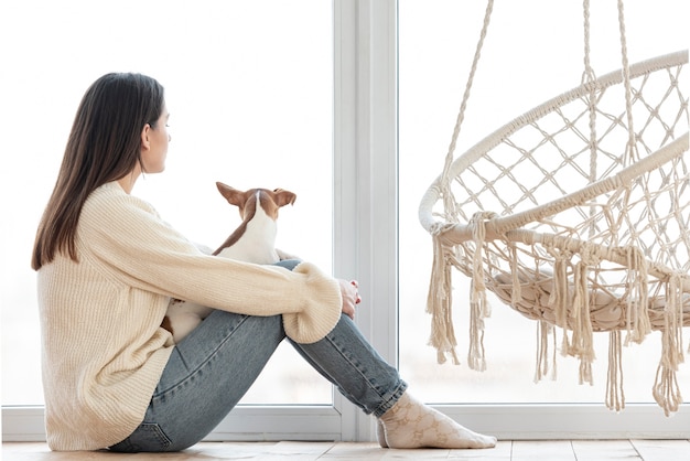 Gratis foto zijaanzicht van vrouw met haar hond naast hangmat