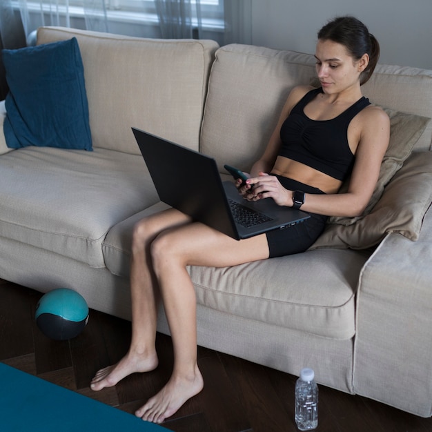 Zijaanzicht van vrouw op bank die aan laptop werkt