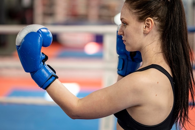 Gratis foto zijaanzicht van vrouwelijke bokser naast ring