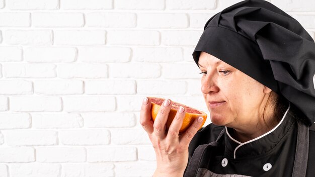 Zijaanzicht van vrouwelijke chef-kok ruikende grapefruit