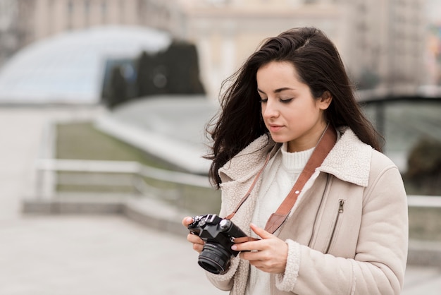 Zijaanzicht van vrouwelijke fotograaf buitenshuis met camera