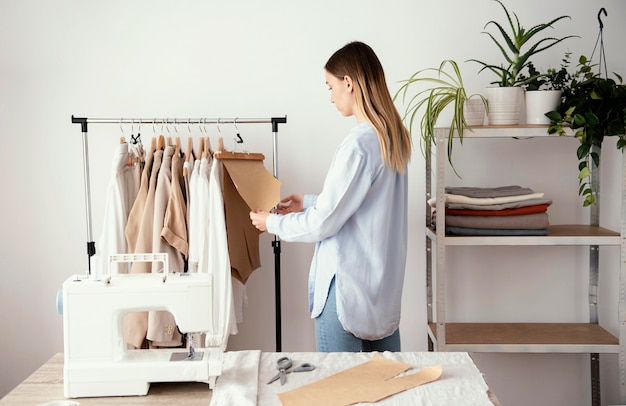 Zijaanzicht van vrouwelijke kleermaker stof voorbereiden op kleding