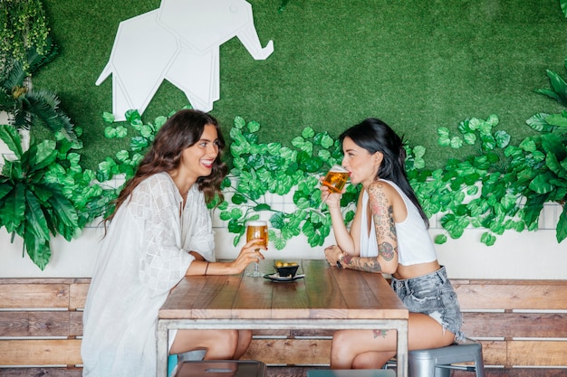 Zijaanzicht van vrouwen die bier drinken aan tafel