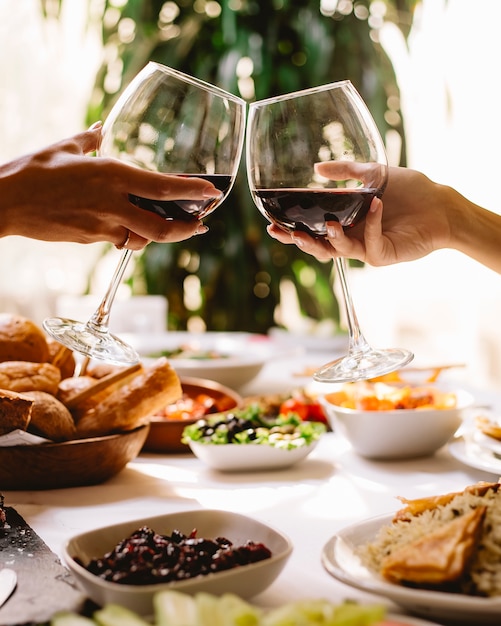 Zijaanzicht van vrouwen die met glazen rode wijn roosteren bij restaurant