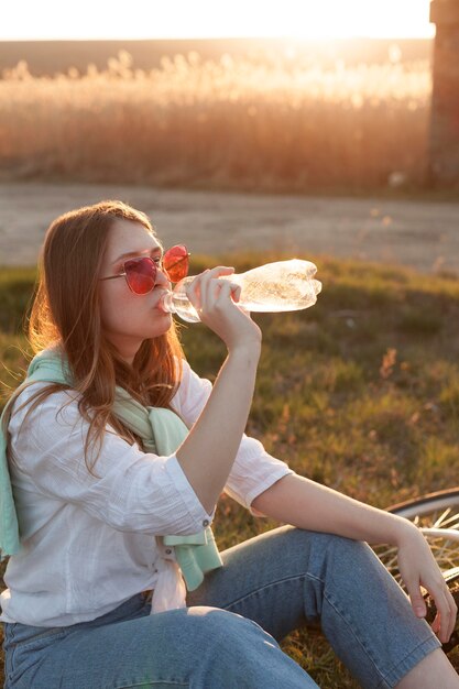 Zijaanzicht van vrouwen drinkwater in de zonsondergang