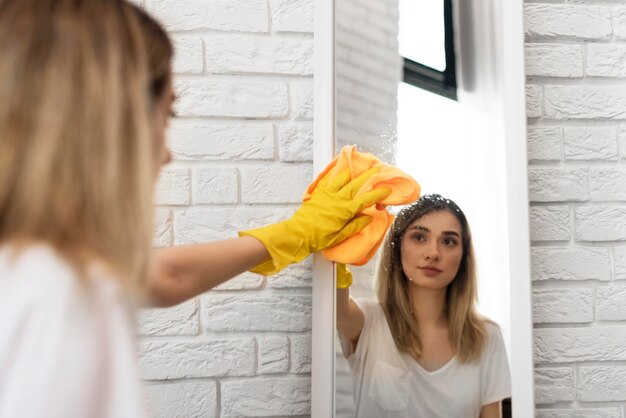 Zijaanzicht van vrouwen schoonmakende spiegel met doek