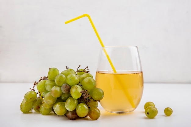 Zijaanzicht van witte druif en druivensap in glas op witte achtergrond