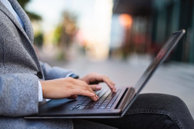 Zijaanzicht van zakenvrouw die op laptop buitenshuis werkt