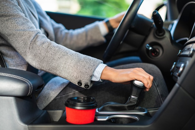 Zijaanzicht van zakenvrouw met behulp van de stick-shift van haar auto