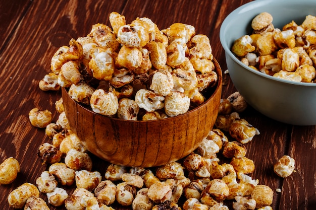 Zijaanzicht van zoete karamel popcorn in een houten kom op rustieke achtergrond