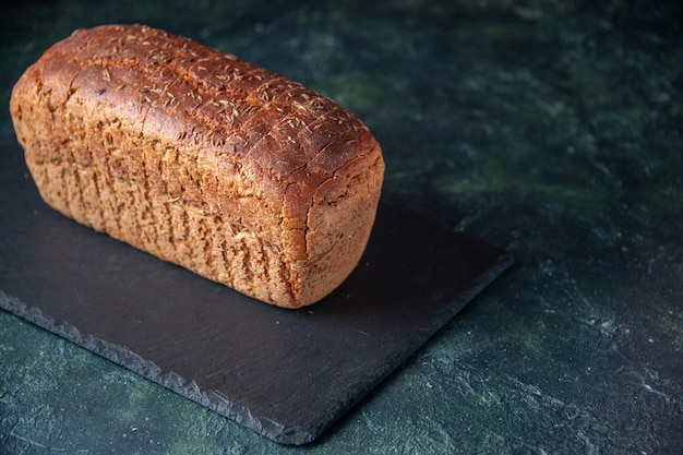 Gratis foto zijaanzicht van zwart brood op zwart bord op gemengde kleuren noodlijdende achtergrond